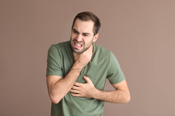 Junger Mann mit Asthmaanfall vor farbigem Hintergrund - Foto, Bild