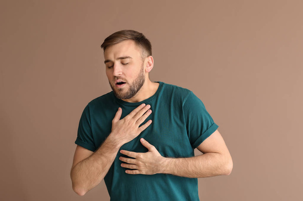 Young man having asthma attack on color background - Foto, afbeelding
