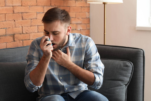 Jeune homme avec inhalateur ayant une crise d'asthme à la maison - Photo, image