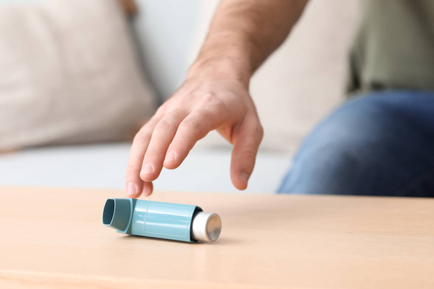 Young man with asthma attack taking inhaler from table, closeup - Foto, Imagen