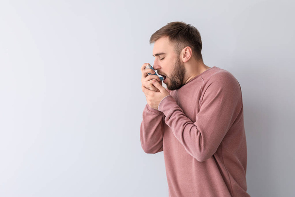 Młody człowiek z inhalatorem z atakiem astmy na białym tle - Zdjęcie, obraz