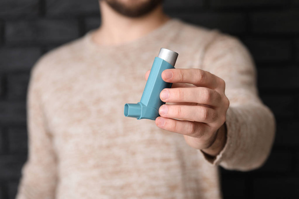 Young man with inhaler on dark background, closeup - Foto, immagini