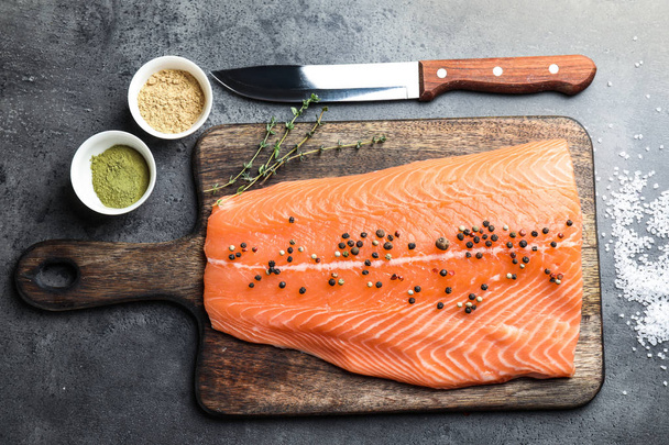 Board with fillet of fresh salmon and knife on table - Фото, зображення