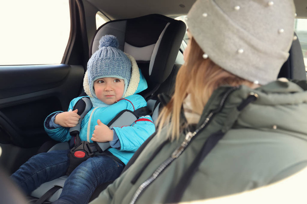Femme conduisant une voiture avec son fils bouclé dans le siège bébé
 - Photo, image