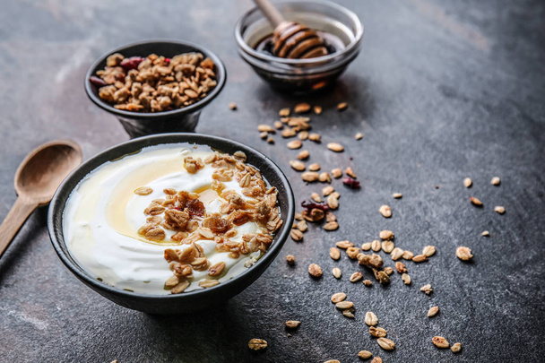 Bowl with tasty yogurt, honey and oatmeal on dark background - Zdjęcie, obraz
