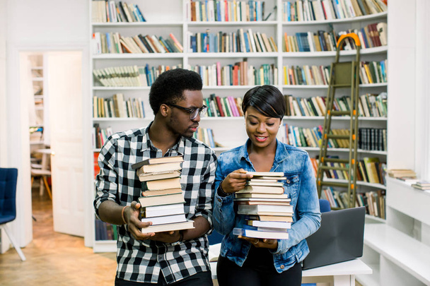Hipster young african american students boy and girl studying in library at the university. Happy smiling couple holding books and having fun in modern library. - Valokuva, kuva