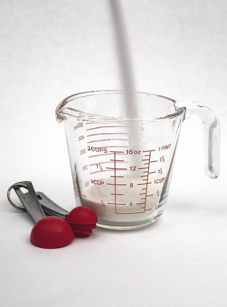 Versare lo zucchero di canna bianco in un misurino con cucchiai dosatori in vista, esposizione nel tempo
. - Foto, immagini