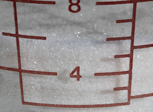 Primo piano dei segni di misurazione dello zucchero di canna bianco in tazza
. - Foto, immagini