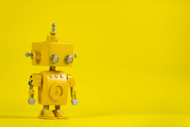 Cute, yellow, handmade robot on a yellow background. - Foto, Imagen