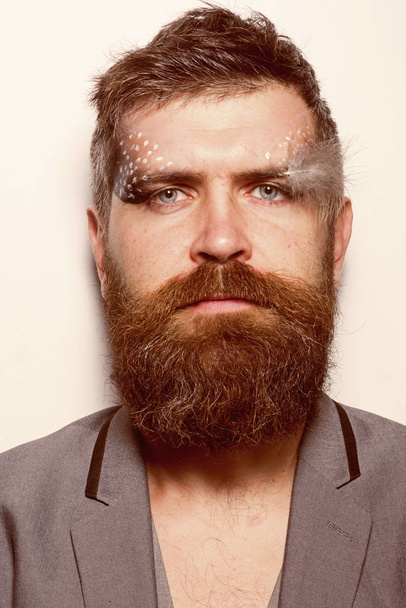 Makeup and make up. Bearded man with creative makeup and feather. Man with long beard and makeup on unshaven face. Fashion art makeup. Beauty is for everyone - Photo, image