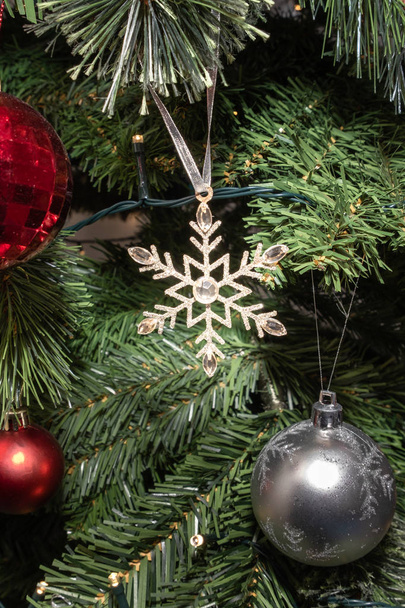 A glittery Christmas Star on a tree surroiunded by bobbles and Christmas lights. - Zdjęcie, obraz