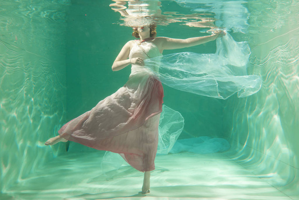 Hot Slim Caucasian Woman Posing Under water in beautiful clothes alone in the deep - Фото, изображение