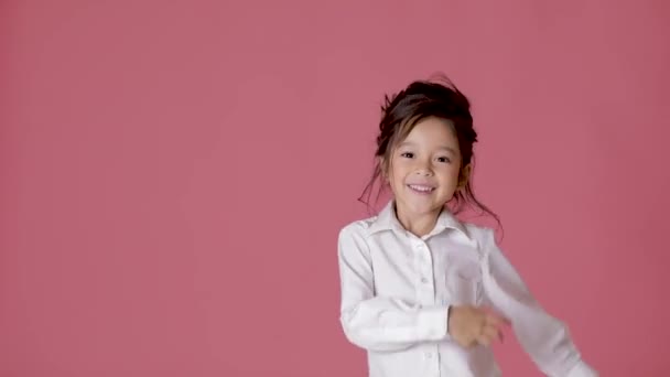 little child girl in white shirt dancing on pink background. - Filmati, video