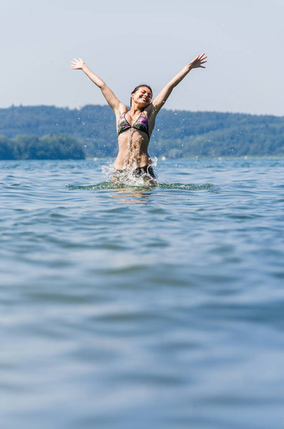молодая женщина, прыгающая в озеро Констанция
 - Фото, изображение
