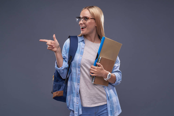 Charming blond girl with documents pointing finger at something interesting - Foto, Bild