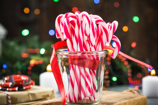 Βάζο με εορταστική καραμέλα από ζαχαροκάλαμο στο χριστουγεννιάτικο τραπέζι. - Φωτογραφία, εικόνα
