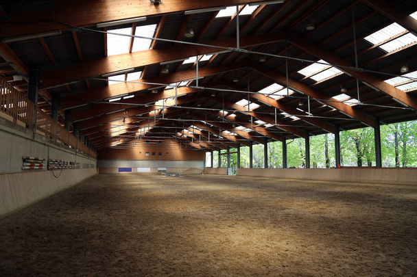 Kijk in een zaal van het indoor rijden voor paarden en ruiters. De manege is geschikt voor de dressuur en springen paard - Foto, afbeelding