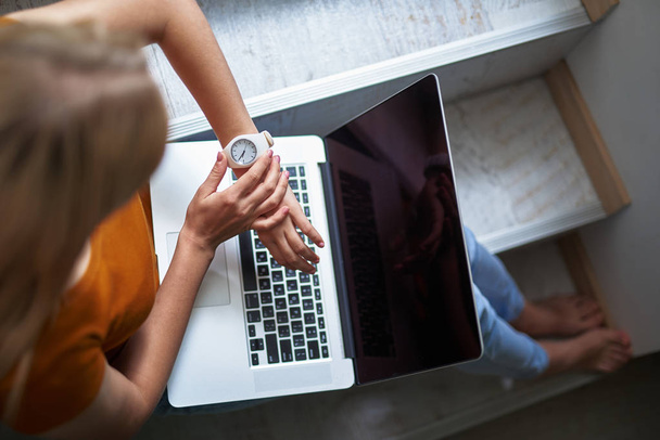 Дівчина з сучасним ноутбуком дивиться на її наручний годинник
 - Фото, зображення