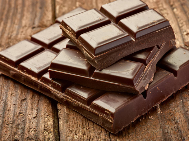 close up de pedaços de chocolate no fundo de madeira - Foto, Imagem