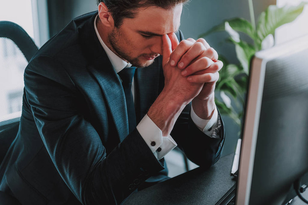 Tired young businessman touching his face and closing eyes - Foto, afbeelding