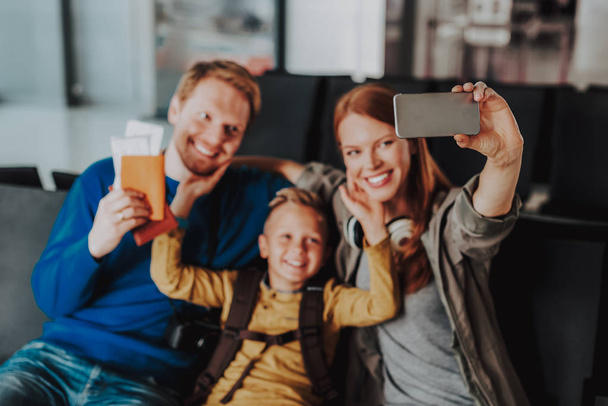 Smiling parents with boy are taking selfie at airport - Fotó, kép