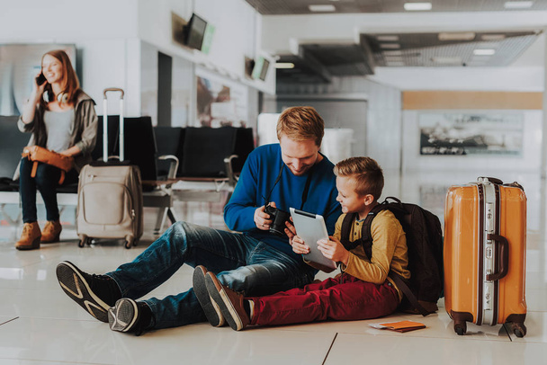 Joyeux papa et fils utilisent des appareils modernes à l'aéroport
 - Photo, image