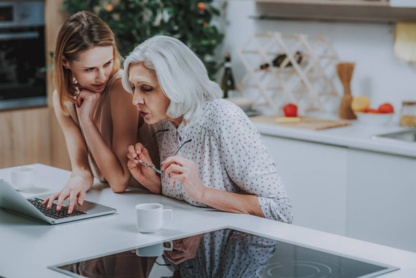 Young woman and mother are spending time with laptop indoor - Photo, image