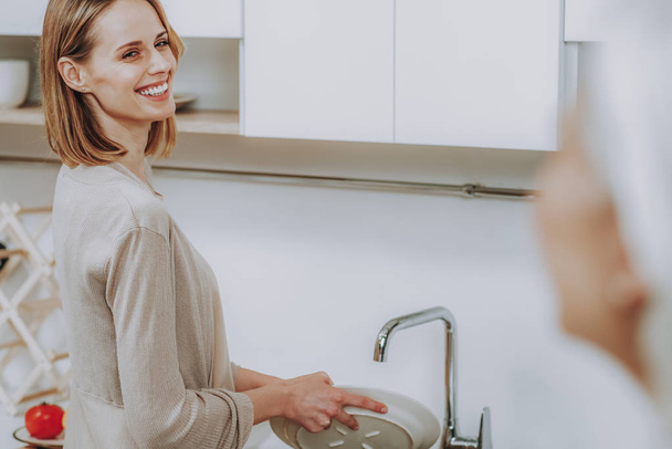 Веселая женщина моет посуду дома
 - Фото, изображение