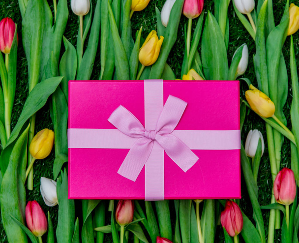 Geschenkbox und Tulpen auf grünem Rasen - Foto, Bild