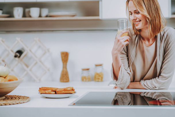 Smiling woman is having fresh drink at home - Photo, Image
