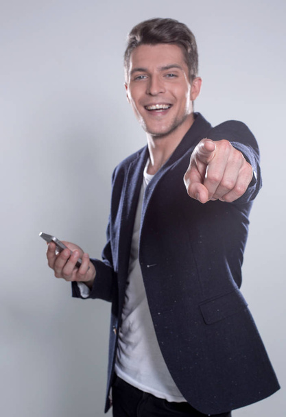 Young cheerful guy smiling looking at smartphone - Фото, изображение