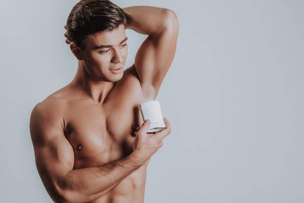 Calm topless man standing with deodorant near the armpit - Zdjęcie, obraz