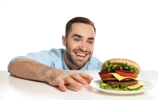 白い背景の上のおいしいハンバーガーと若い飢えた男 - 写真・画像