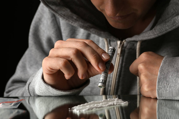 Drug addict taking cocaine at table, closeup view - Фото, зображення