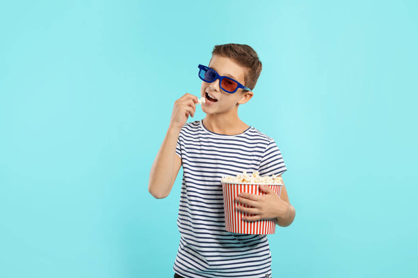 Boy with 3D glasses and popcorn during cinema show on color background - Foto, Bild