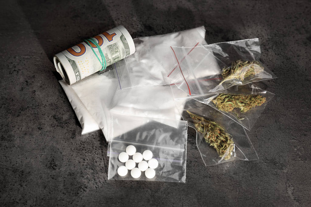 Plastic bags with cocaine, pills, hemp buds and money on grey background - Photo, Image