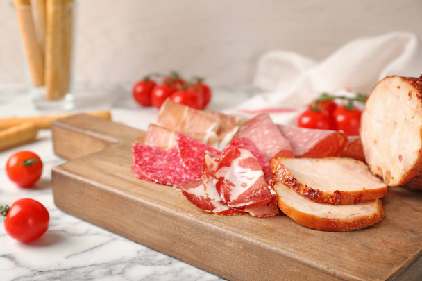 Tabla de cortar con diferentes manjares de carne en la mesa de mármol
 - Foto, imagen