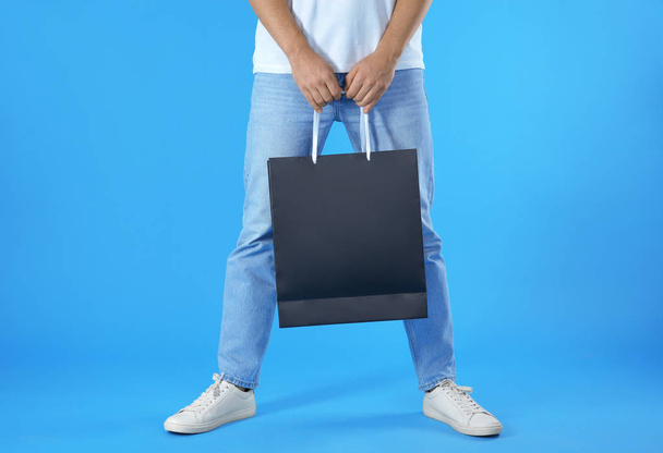 Young man holding paper bag on color background, closeup.  Mockup for design - Foto, imagen