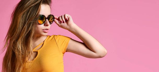 Cheerful young woman in sunglasses against pink background. - Zdjęcie, obraz