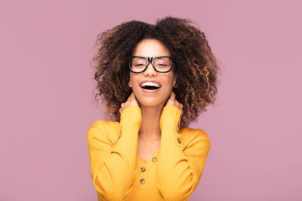 Happy african american woman smiling. Beautiful female half-length portrait. Young emotional afro woman. The human emotions, facial expression concept. Pink background. - Fotó, kép