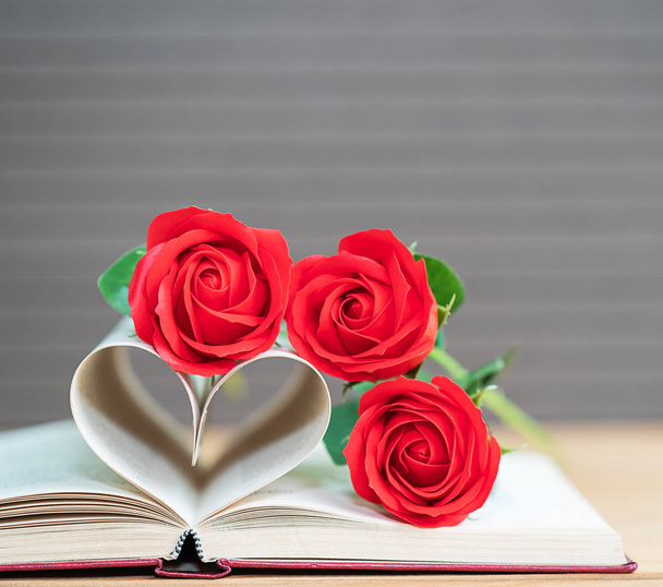 Buchseiten in Herzform und roter Rose gebogen, Liebeskonzept der Herzform aus Buchseiten - Foto, Bild