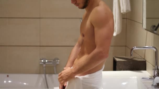 Shirtless muscular handsome young man looking at himself in bathroom mirror in the morning - Záběry, video