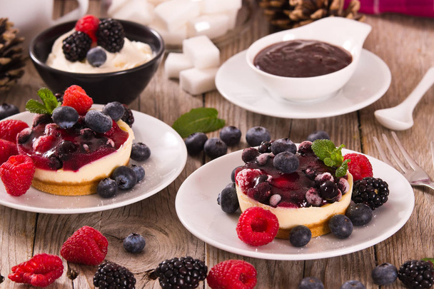Cheesecakes with mixed berries on white dish. - Photo, Image