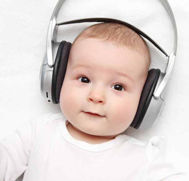 bebê com fone de ouvido encontra-se nas costas
 - Foto, Imagem