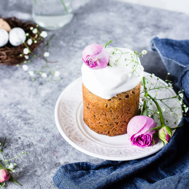 イースター ケーキ クリーチ。伝統的なイースターの甘いパンには、メレンゲと灰色の石のテーブル背景にプレートにピンクのバラが装飾されています。コピー スペース. - 写真・画像