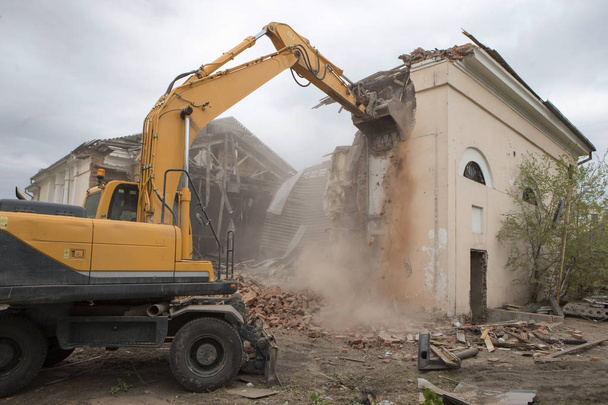 La destruction des murs de l'ancien bâtiment et le nettoyage des débris de construction avec un seau d'une pelle. - Photo, image