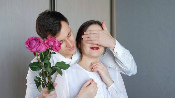 Человек закрывает его подруги глаза, чтобы сделать сюрприз и дает розы
 - Фото, изображение