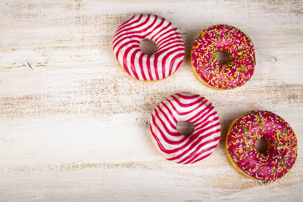 Pink donuts on a wooden background. Delicious dessert. - Foto, afbeelding