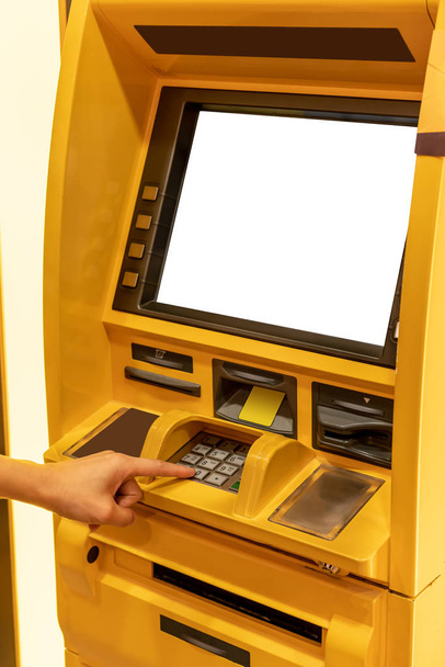 Close up of hand entering pin at an ATM. Finger about to press a pin code on a pad. Security code on an Automated Teller Machine. Female arms, yellow ATM - Photo, Image