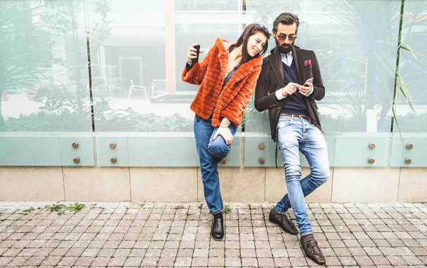 Happy hipster couple having fun with mobile smart phone at outdoors location - Friendship concept with best friends connecting and sharing content on social media - Millennial generation dating online - Photo, Image